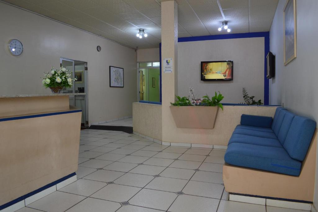 a waiting room with a blue couch in a hospital at Touring Hotel in Maringá