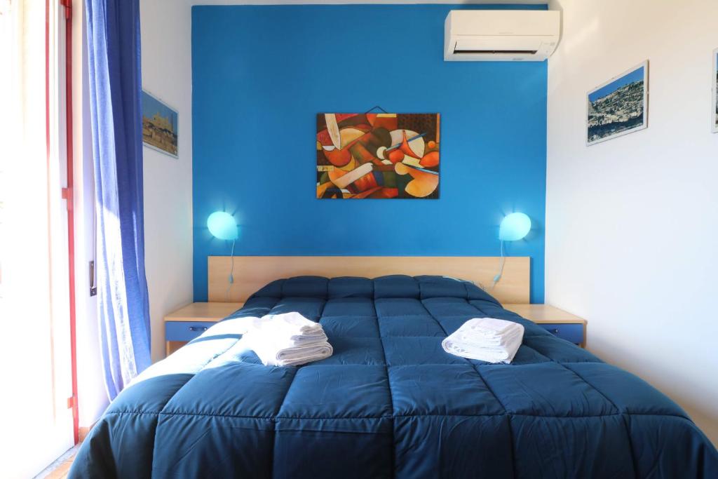 a blue bedroom with a bed and a painting on the wall at B&B Spiaggia di Ponente in Scicli