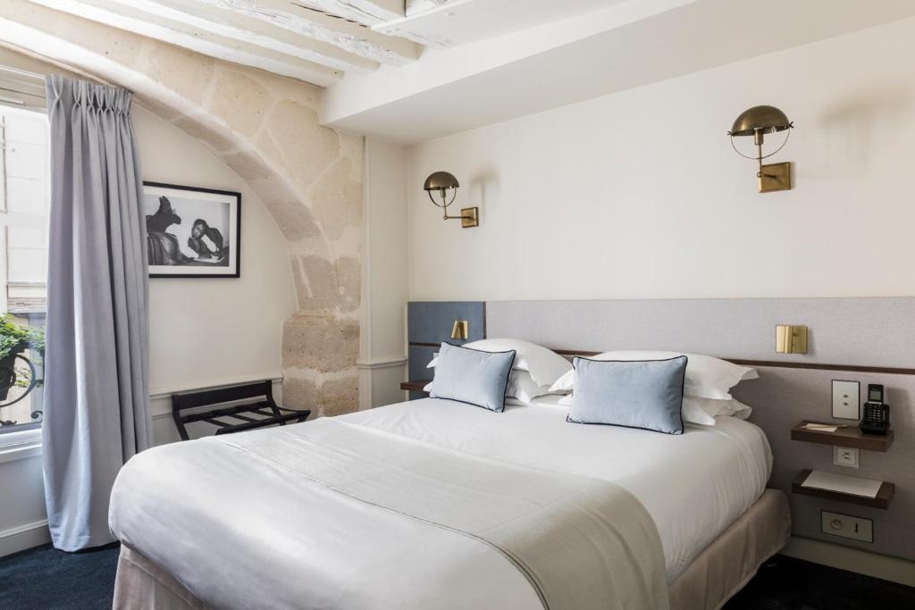 a bedroom with a large white bed and a window at Hotel Verneuil Saint Germain in Paris