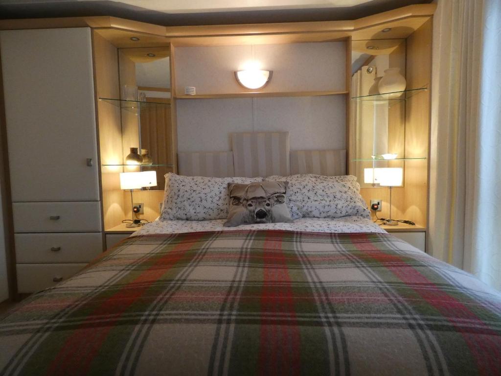 - une chambre avec un grand lit avec un chien dans l'établissement Crossbill Chalet - 71, à Boat of Garten