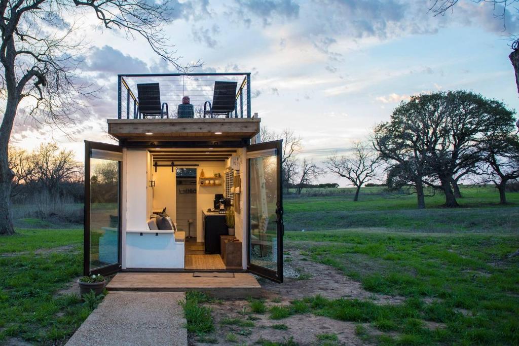 a tiny house with a balcony on top of it at Stillwater House Elegant tiny container home Near Magnolia in Waco