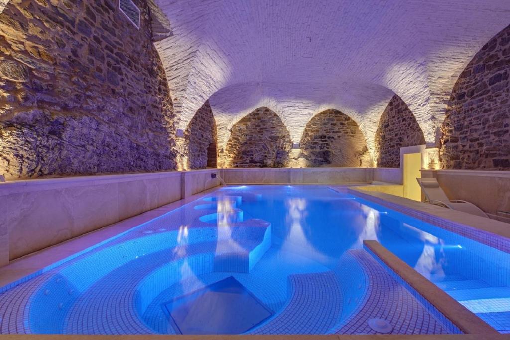 an indoor swimming pool in a building with stone walls at Monastero Di Cortona Hotel & Spa in Cortona