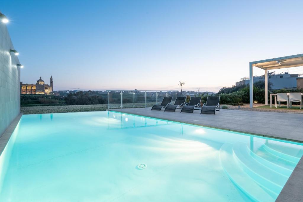 a swimming pool with chairs on the roof of a house at Twilight Holiday Home in Għasri