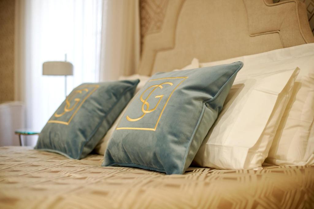a bed with two blue and white pillows on it at Signature Apartments Os Terceiros in Braga