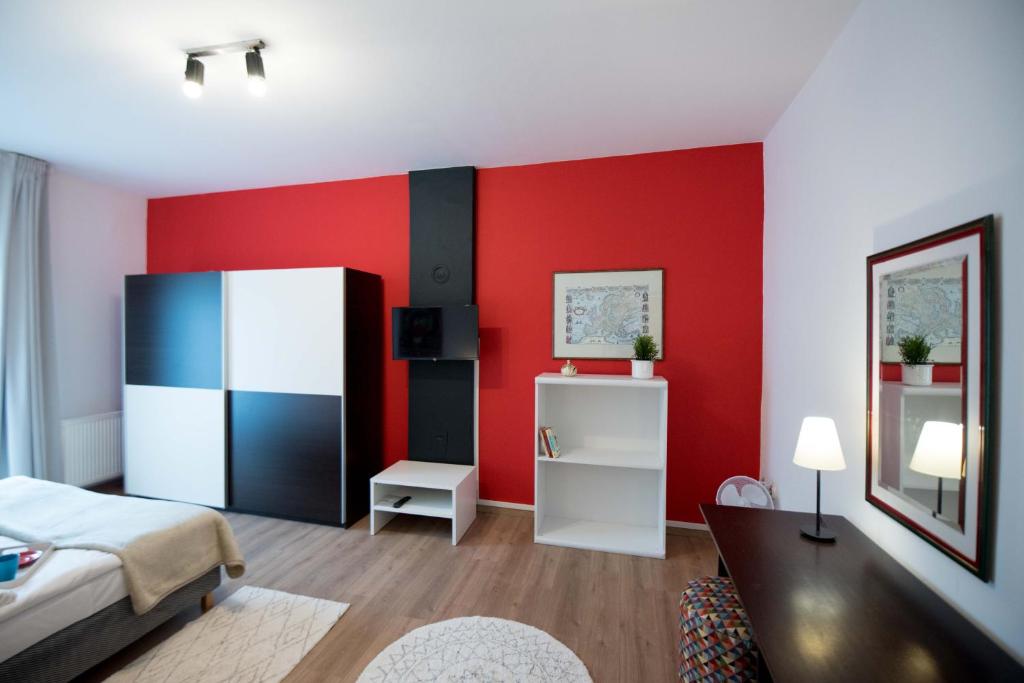 a bedroom with a red wall with a bed and a desk at Apartman Isabella in Daruvar