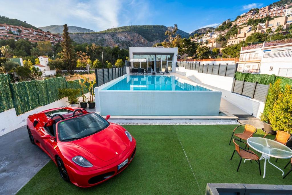 un coche rojo estacionado en la parte superior de una casa con piscina en Luxurious Villa Marly I to two minutes the beach, en Castelldefels