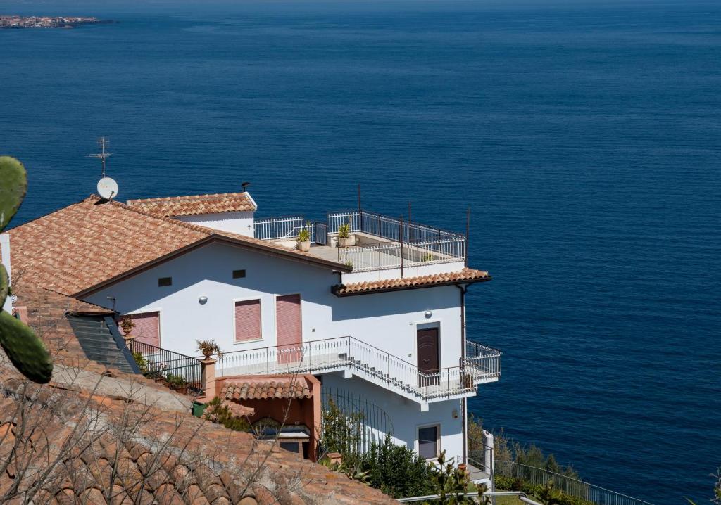 a house on the side of a hill overlooking the ocean at La Timpa in Acireale