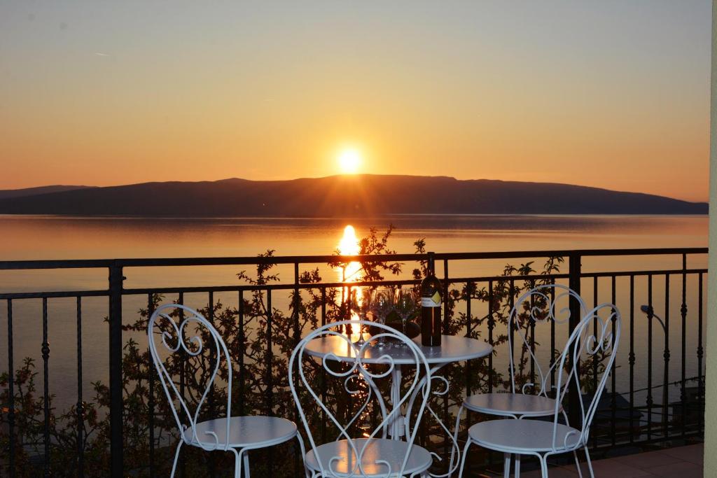 a table and chairs with the sunset in the background at Tri sriće in Senj