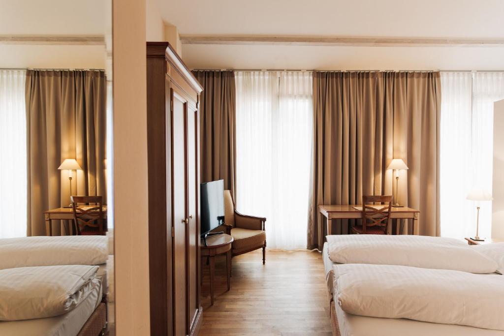 a hotel room with three beds and a television at Kulturbrauerei Heidelberg in Heidelberg