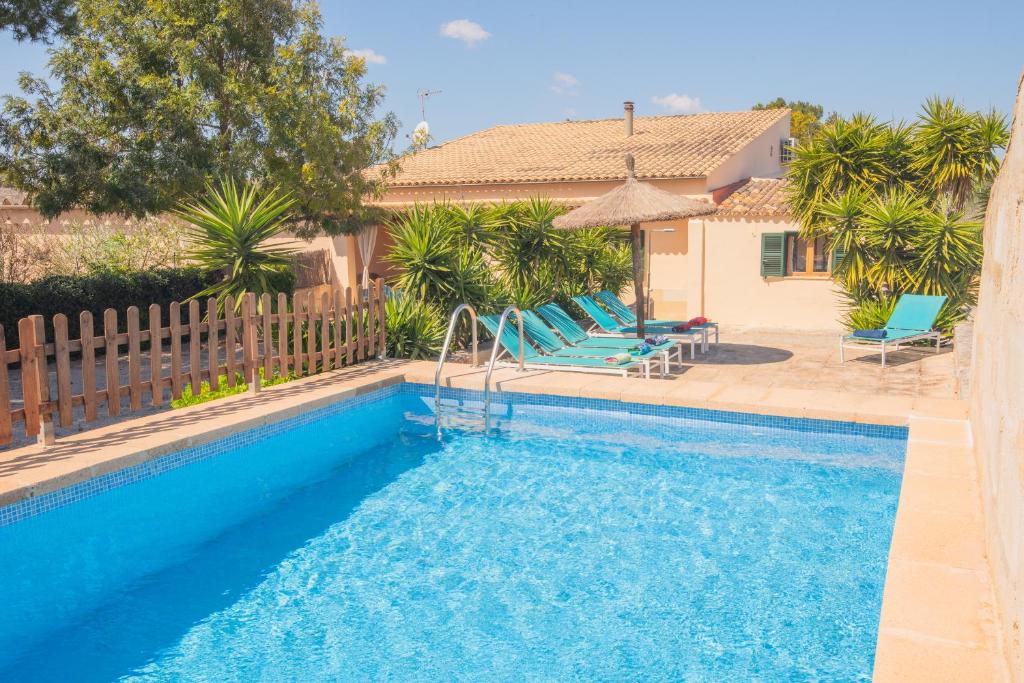 une piscine avec des chaises bleues et une maison dans l'établissement Finca Can Mateu, à Campos