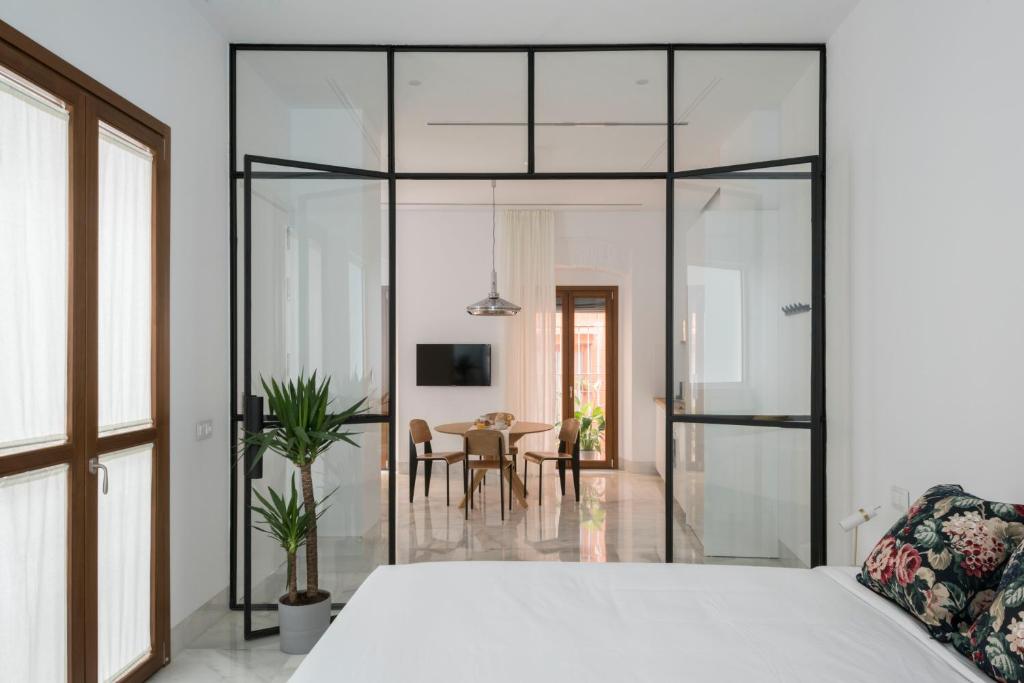 a bedroom with a white bed and a dining room at La casa del Lagar 10 in Seville