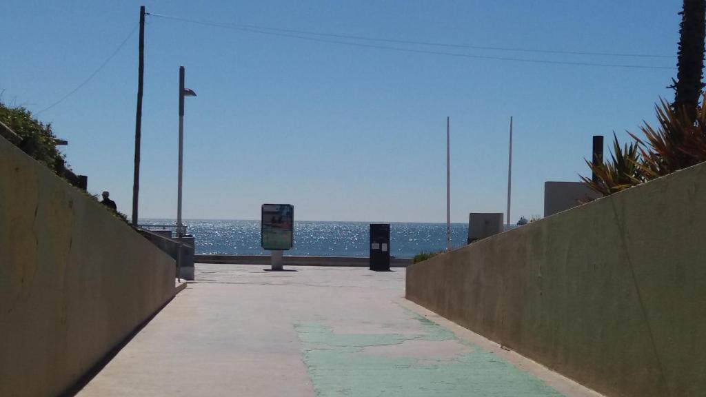 a walkway to the beach with the ocean in the background at Beach House Cascais in Estoril
