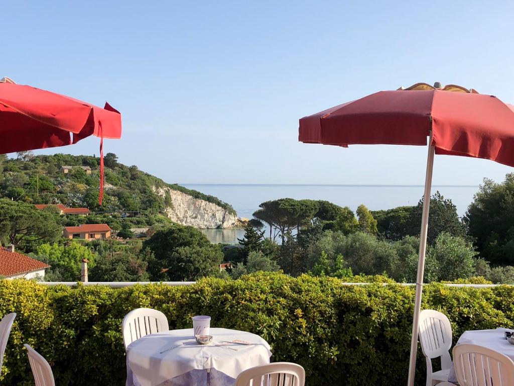 two tables and chairs with umbrellas and the ocean at Hotel Acquamarina in Portoferraio