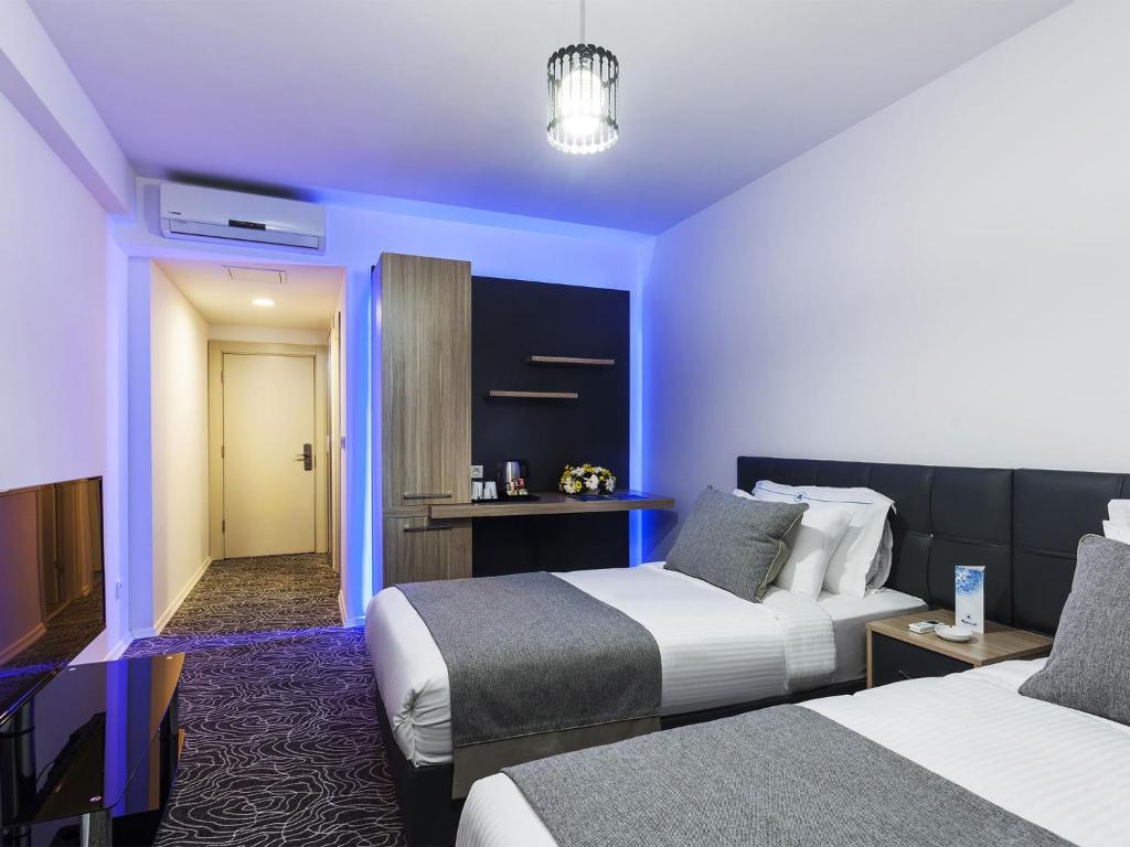 a hotel room with two beds and a television at Merze Suite Konaklama in Beylikduzu