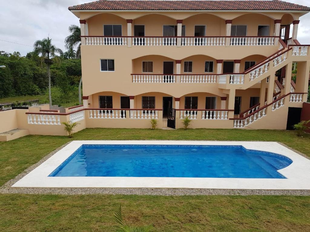 a villa with a swimming pool in front of a house at Apartamentos Nuevo Amanecer in Río San Juan