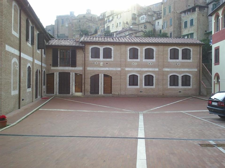 un aparcamiento vacío frente a un edificio en Soggiorno La Primula, en Siena