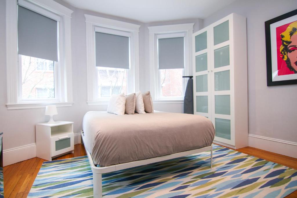 een slaapkamer met een bed met een tapijt en ramen bij A Stylish Stay w/ a Queen Bed, Heated Floors.. #34 in Brookline