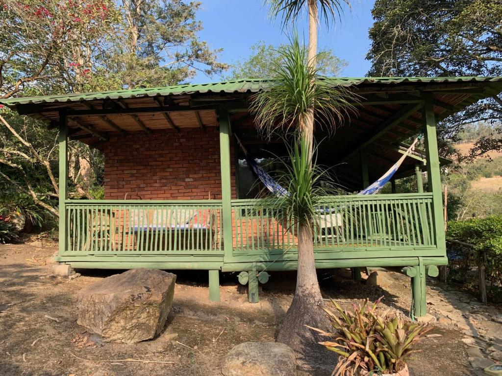 a green house with a hammock in front of a tree at La Trini in Choachí