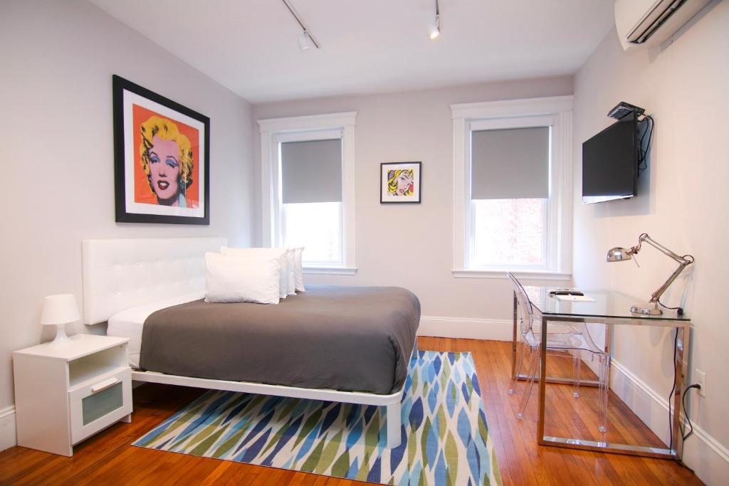 a bedroom with a bed and a desk and windows at A Stylish Stay w/ a Queen Bed, Heated Floors.. #35 in Brookline