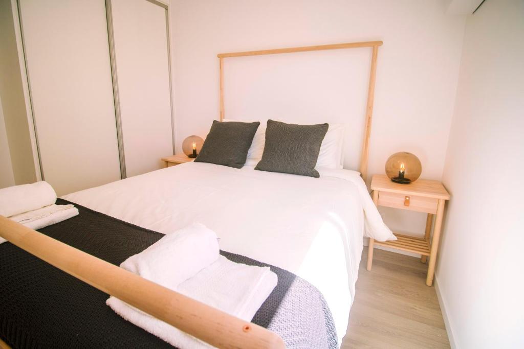1 dormitorio con 1 cama blanca grande y 1 silla en Top Floor Beach Apartment by Silver Prop, en Nazaré