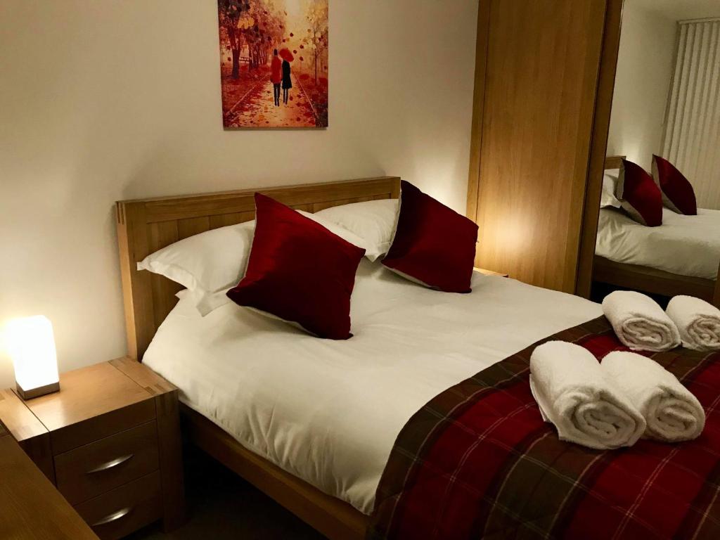 a bedroom with two beds with red and white pillows at exploreNESS Apartment in Inverness