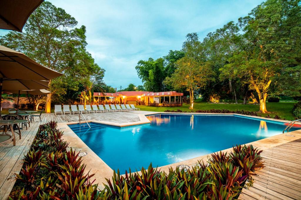 een zwembad in een tuin met een houten terras bij Hotel Chichen Itza in Chichén-Itzá