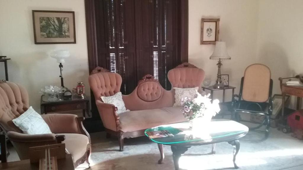 a living room with two chairs and a couch and a table at Smithville Historical Museum and Inn in Smithville