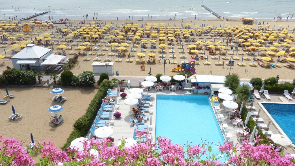 eine Luftansicht auf einen Strand mit Pool und Sonnenschirmen in der Unterkunft Hotel Oxford in Lido di Jesolo