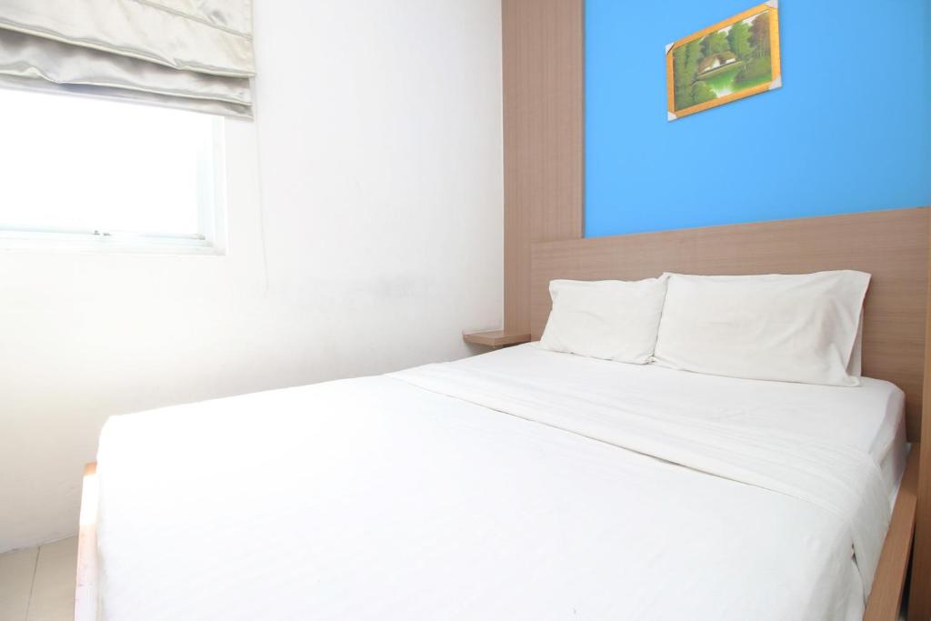 Cama blanca en habitación con ventana en Residence100, en Yakarta