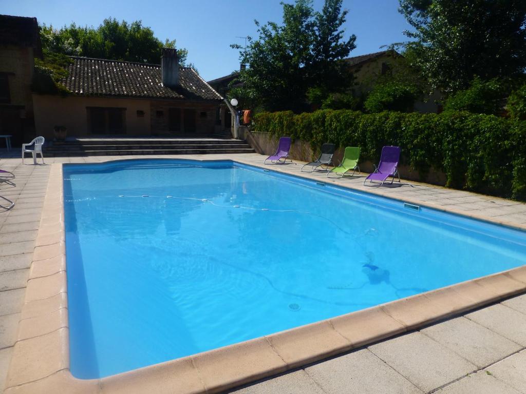 - une grande piscine bleue avec des chaises dans la cour dans l'établissement Chambres d'Hôtes des trouilles, à Lafrançaise