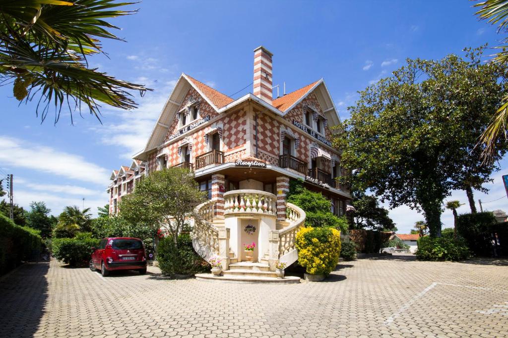 a house with a car parked in front of it at Hôtel Le Dauphin in Arcachon