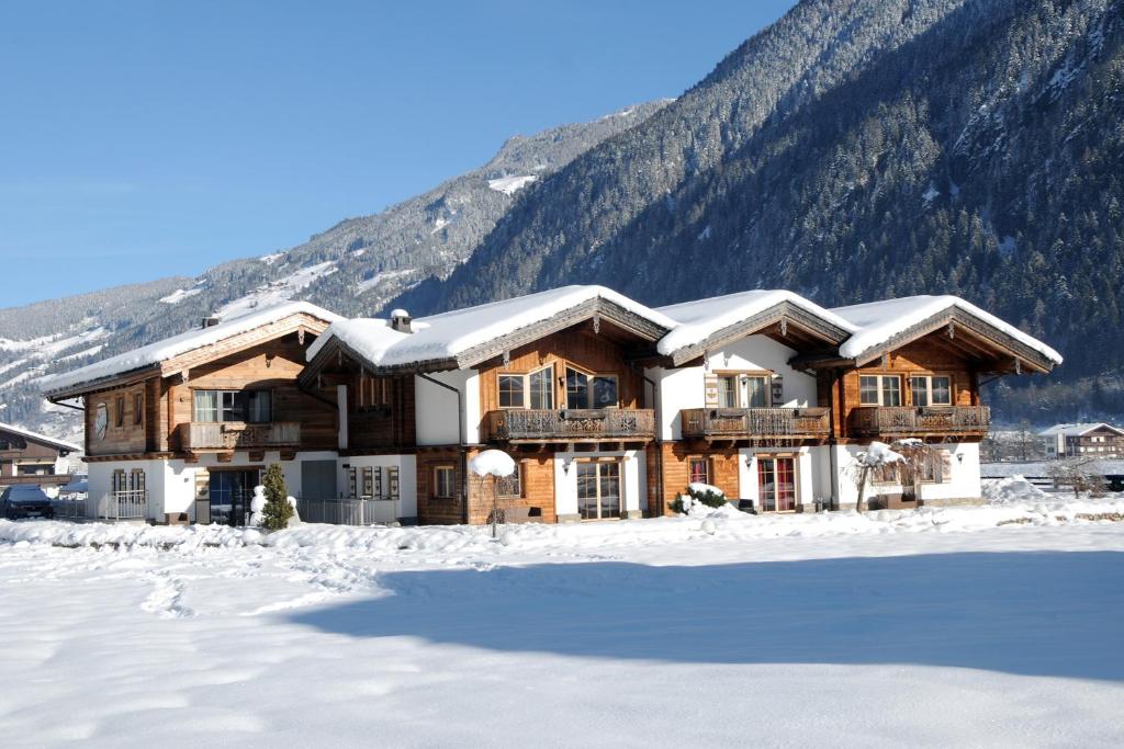 une maison en rondins dans la neige avec une montagne dans l'établissement Chalet Schnee, à Mayrhofen