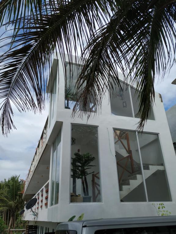 Casa blanca con ventanas grandes y palmera en Damara Beachfront Resort en Baler