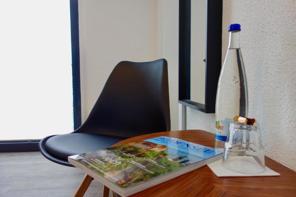 einen Tisch mit einem Stuhl und einer Flasche darauf in der Unterkunft Hotel Seeadler in Friedrichshafen