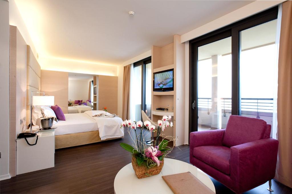 una camera d'albergo con letto e sedia viola di Laguna Palace Hotel Grado a Grado