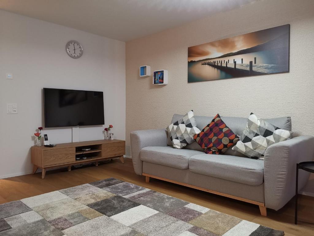 uma sala de estar com um sofá e uma televisão de ecrã plano em Via stenna em Flims