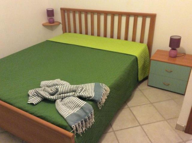 a bedroom with a green bed with towels on it at Casa Esperanto in Favignana