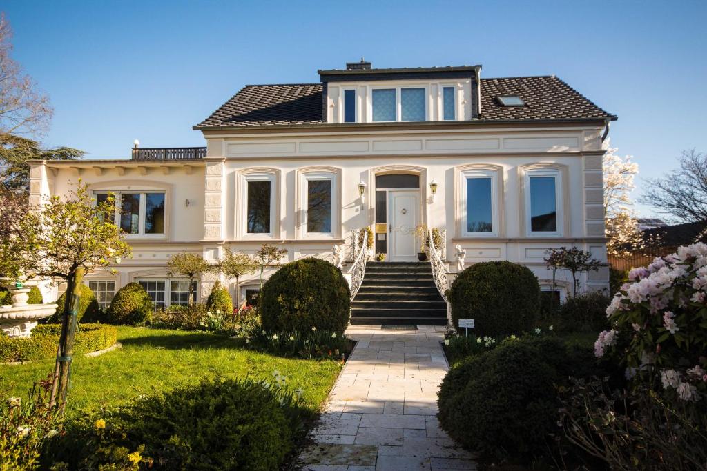 a large white house with a staircase in a yard at Villa Rosengarten in Fehmarn