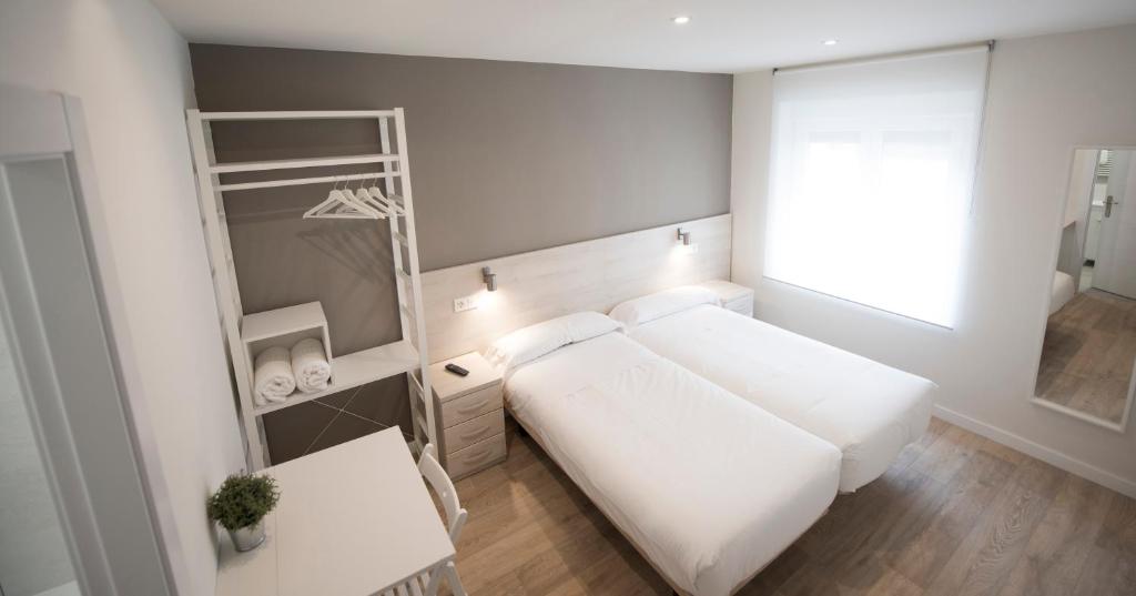 Un pequeño dormitorio con una cama blanca y un estante en Happy Hostal Carrales, en Burgos