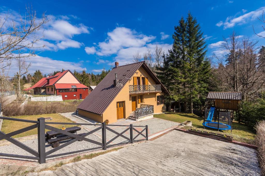 uma casa com um parque infantil em frente em Kuća za odmor Villa.ris em Lokve