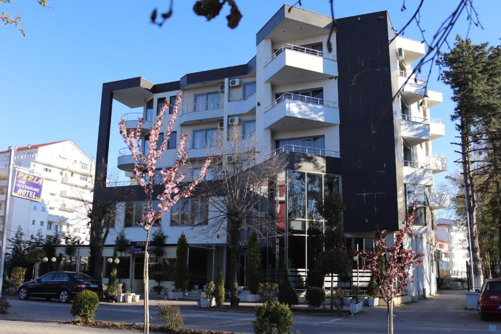 ein hohes weißes Gebäude in einer Stadtstraße in der Unterkunft Perla Hotel in Pogradec