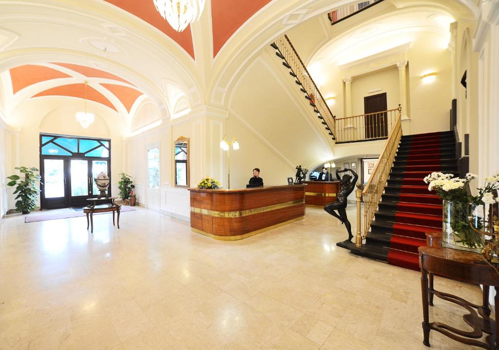 ポンペイにあるホテル リストランテ ヴィットリアの階段のあるロビーとテーブルに座る男性