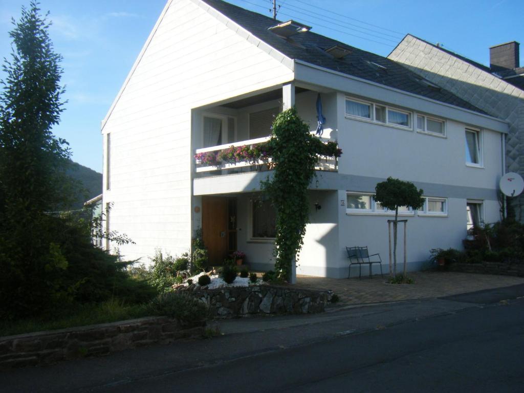 a white house with a balcony on the side of it at Ferienwohnung M. Lemmermeyer in Neumagen-Dhron