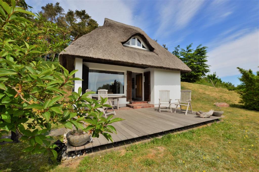 a thatch roof house with a wooden deck at Haus am Hügel in Groß Zicker