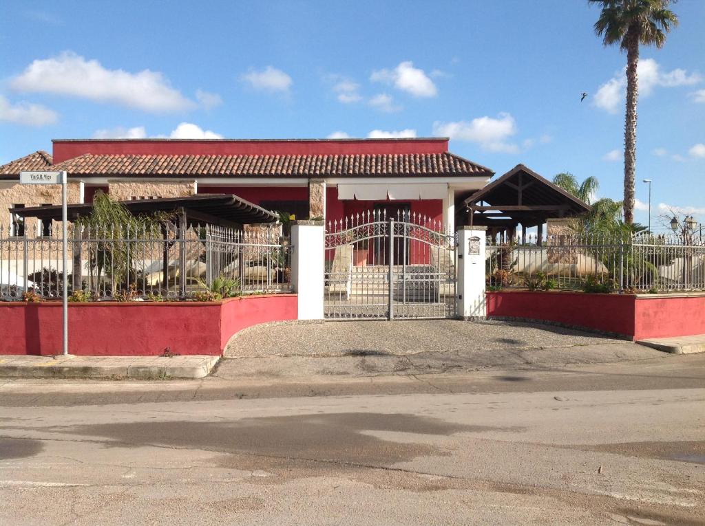 czerwono-biały budynek z bramą i palmą w obiekcie Villa nel cuore del Salento w mieście Ruffano