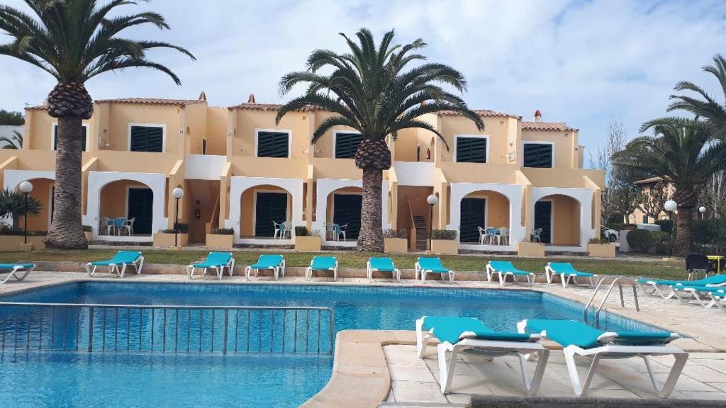 un complejo con piscina y palmeras en Apartamentos Costa Menorca en Cala'n Bosch