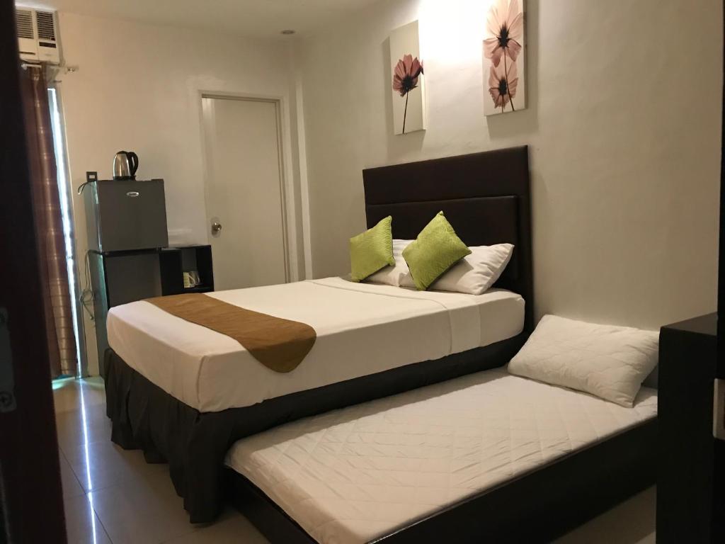a bedroom with two beds with green pillows at The Blanket Hotel Restaurant & Coffee in Ilagan