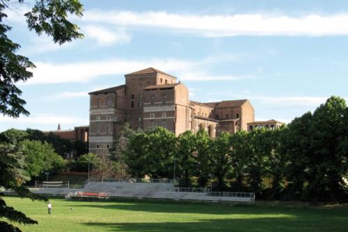 un gran edificio de ladrillo en un campo con árboles en Lu.Lu Suite and Rooms, en Piacenza