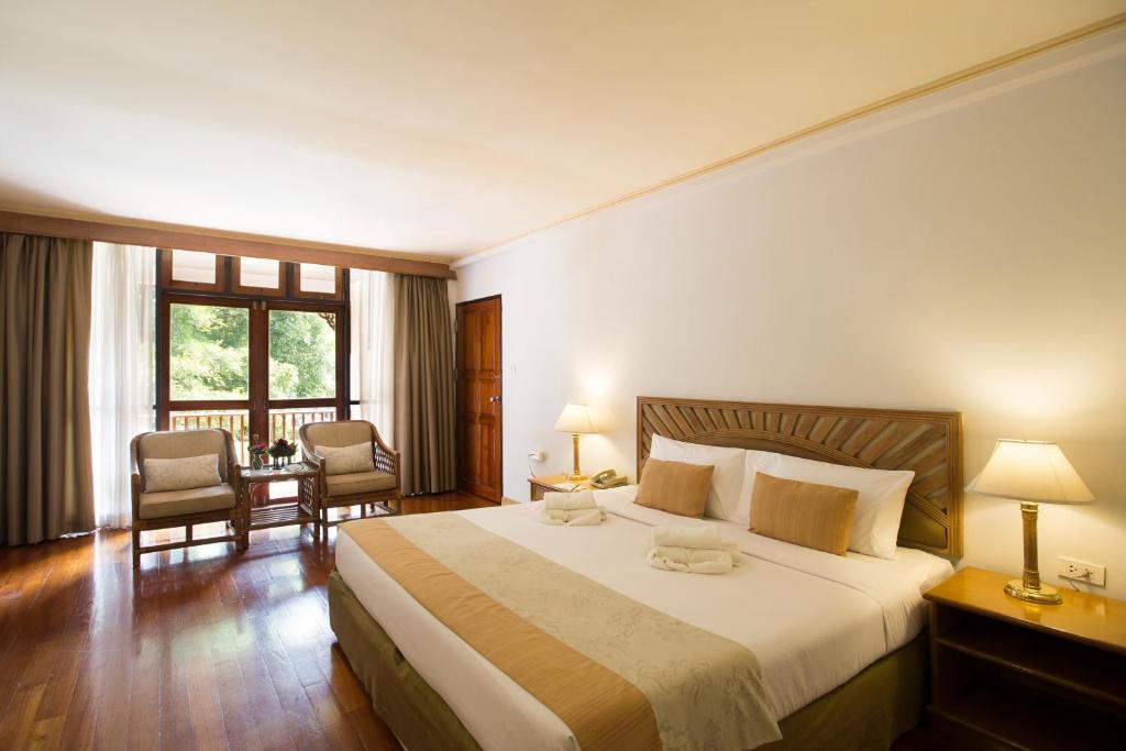 湄宏順的住宿－帝國湄宏順度假酒店，酒店客房带一张大床和两张椅子