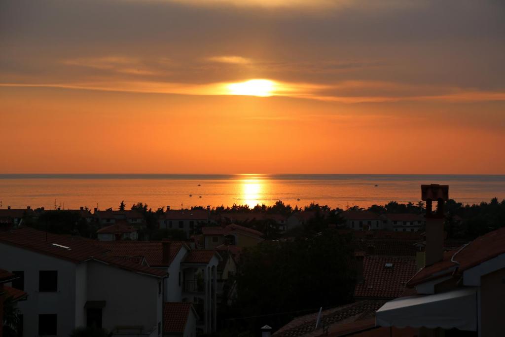 a sunset over the ocean and a city at Apartment Panorama in Poreč